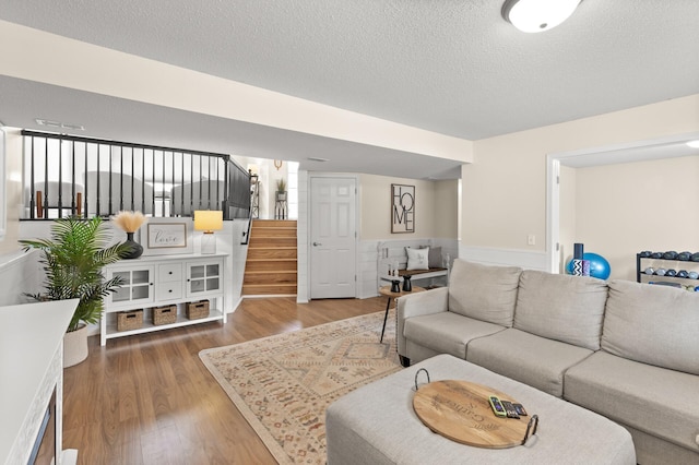 living room featuring wood finished floors, a textured ceiling, and stairs