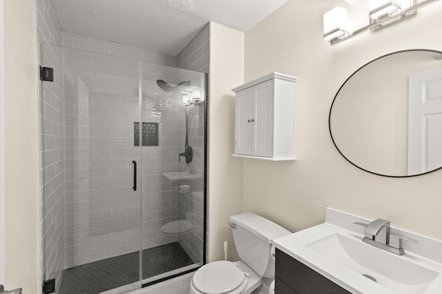 full bath with toilet, a shower stall, a textured ceiling, and vanity