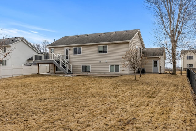 back of property with a shingled roof, a fenced backyard, stairs, a deck, and a yard