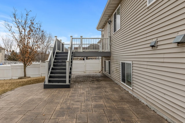 view of home's exterior with a patio area, fence, and stairway