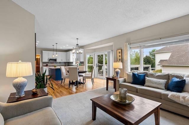 living room featuring a textured ceiling, light wood finished floors, recessed lighting, and an inviting chandelier