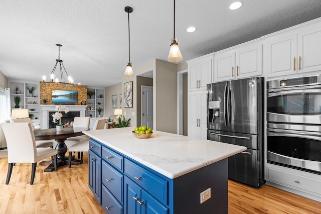 kitchen featuring a textured ceiling, a fireplace, white cabinetry, appliances with stainless steel finishes, and blue cabinetry