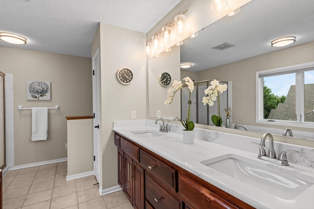 bathroom featuring tile patterned flooring, a shower stall, and a sink