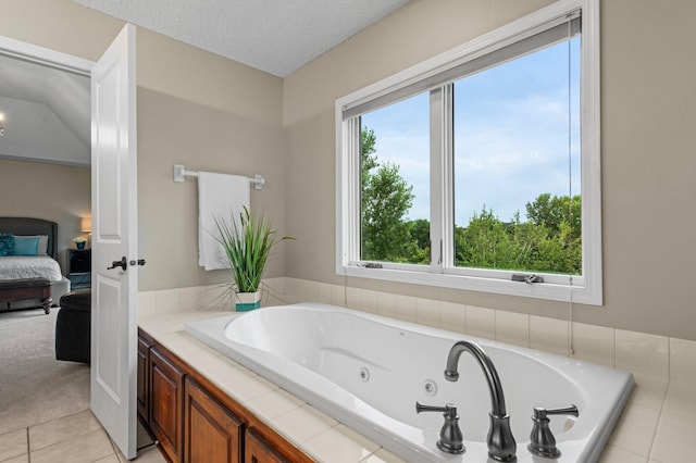 ensuite bathroom with a textured ceiling, a jetted tub, ensuite bathroom, and tile patterned floors