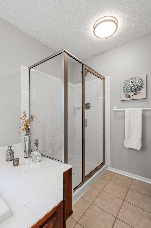 bathroom with a shower stall, a textured ceiling, and tile patterned flooring