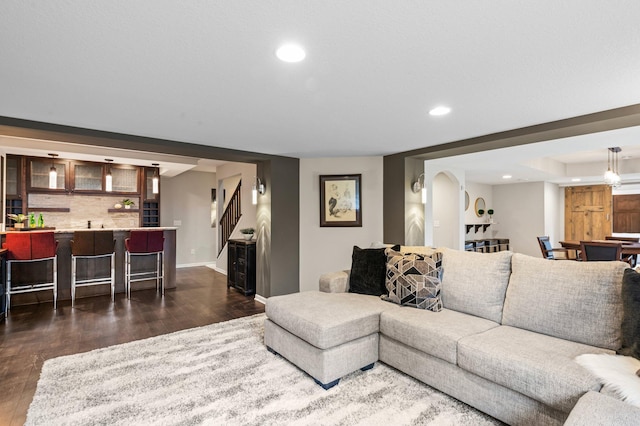 living area with baseboards, dark wood-type flooring, stairway, and recessed lighting