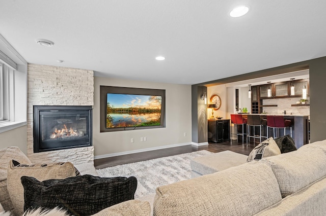 living area with wet bar, baseboards, a fireplace, and dark wood-style flooring