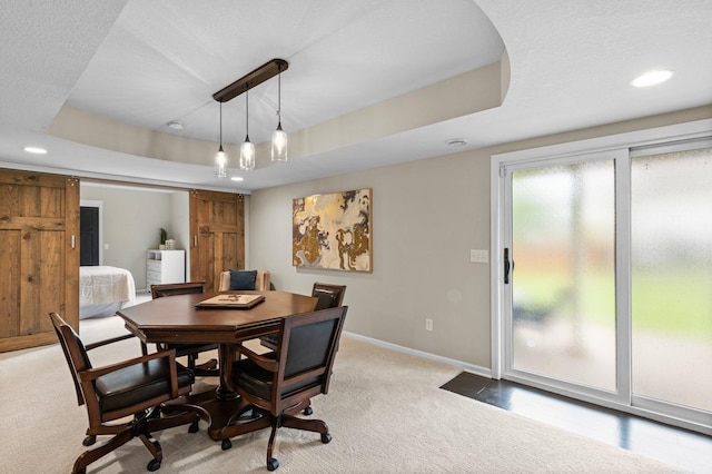 dining area featuring recessed lighting, a raised ceiling, a barn door, light carpet, and baseboards