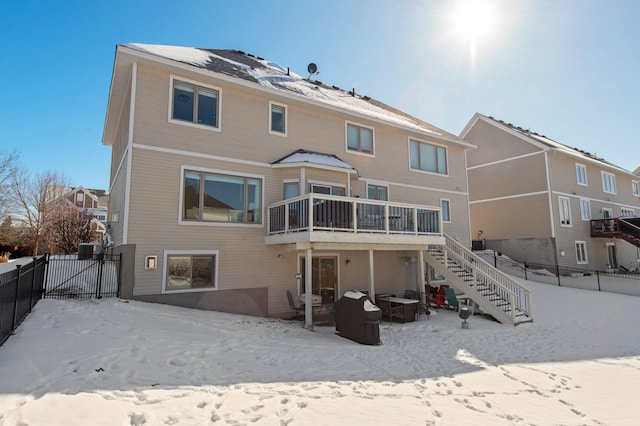 snow covered property featuring fence, stairway, and a deck