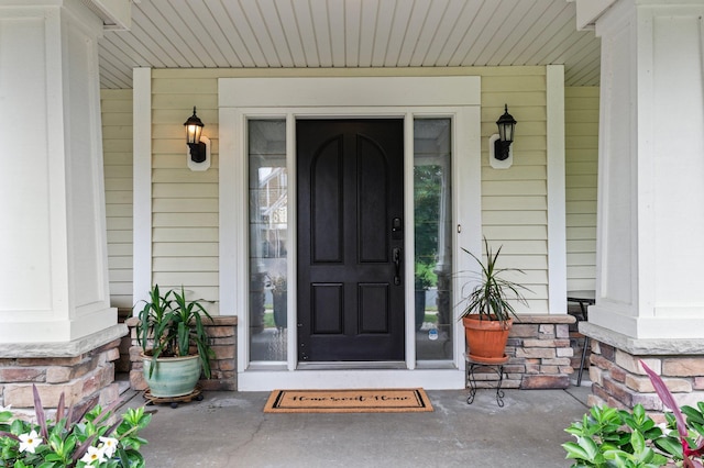 view of exterior entry featuring stone siding and a porch