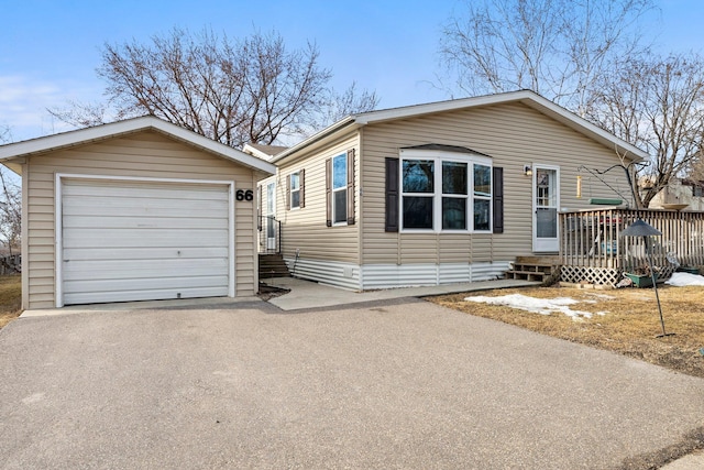 view of front facade with aphalt driveway, a garage, an outdoor structure, and a wooden deck