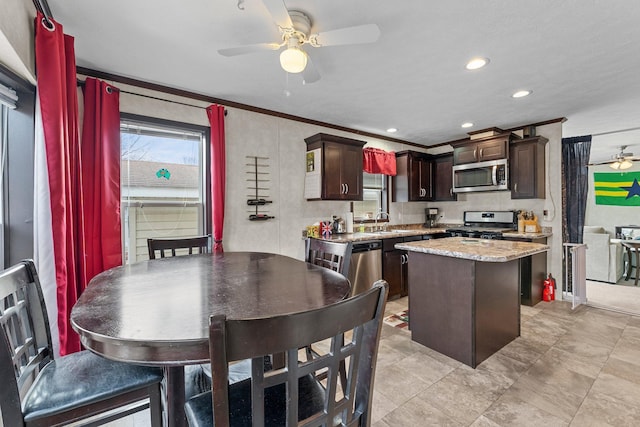 kitchen with ornamental molding, a sink, a kitchen island, appliances with stainless steel finishes, and ceiling fan