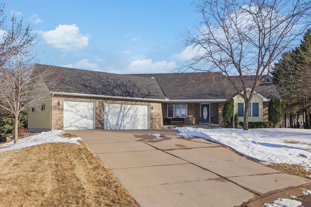 ranch-style house featuring brick siding, an attached garage, concrete driveway, and a shingled roof