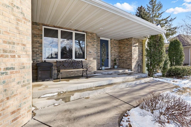 property entrance with covered porch and brick siding