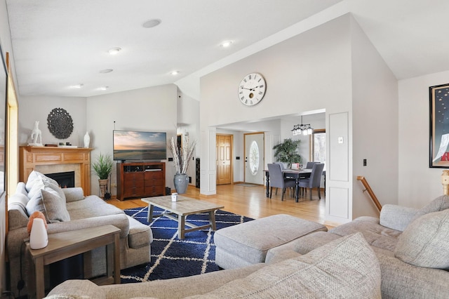 living area with a premium fireplace, recessed lighting, high vaulted ceiling, and wood finished floors