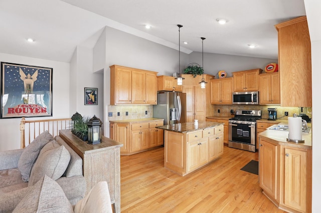 kitchen featuring light wood finished floors, a kitchen island, light brown cabinetry, open floor plan, and appliances with stainless steel finishes