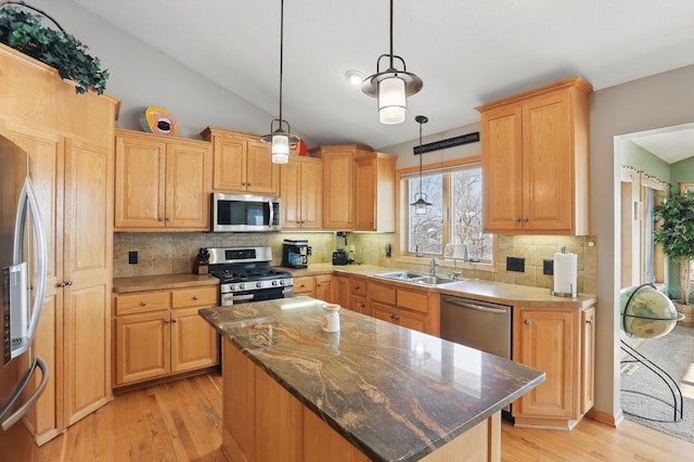 kitchen featuring a sink, vaulted ceiling, light wood-style flooring, and stainless steel appliances