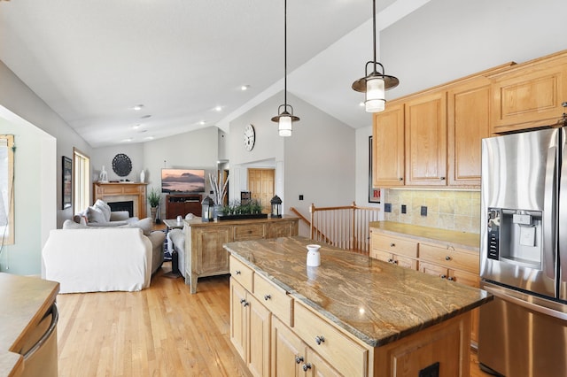 kitchen with light wood finished floors, stainless steel fridge with ice dispenser, vaulted ceiling, decorative backsplash, and a fireplace