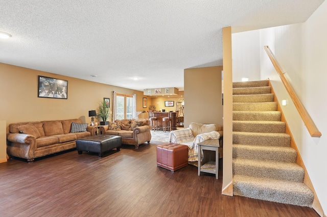 living area featuring a textured ceiling, dark wood finished floors, and stairs