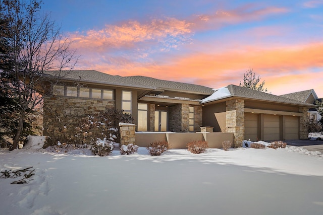 prairie-style home featuring stone siding and an attached garage