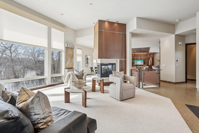 living room with a multi sided fireplace and baseboards