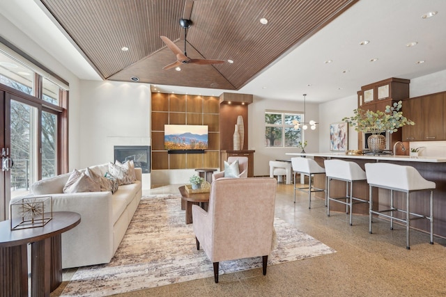 living room featuring light speckled floor, lofted ceiling, wooden ceiling, recessed lighting, and a glass covered fireplace