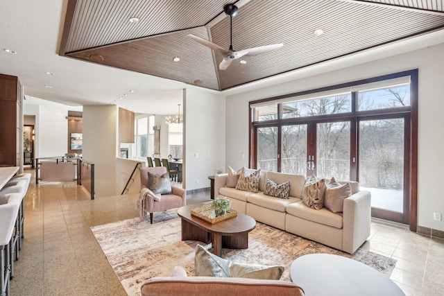 living room featuring recessed lighting, baseboards, and ceiling fan with notable chandelier