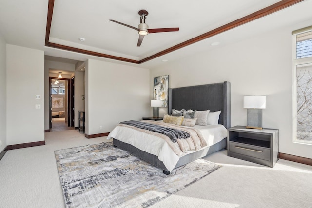 carpeted bedroom with ceiling fan, a tray ceiling, and baseboards