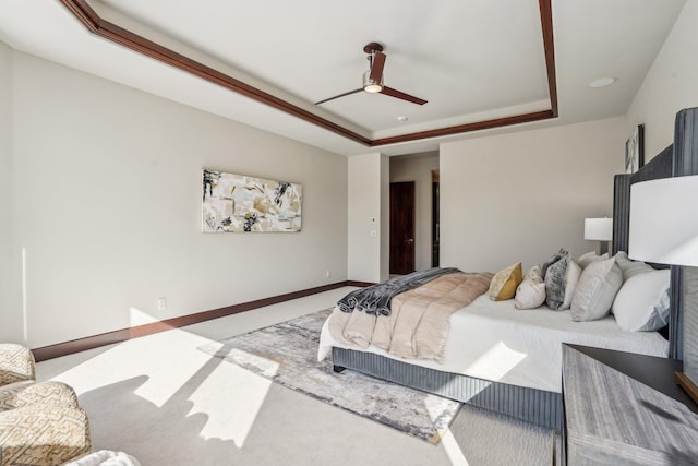 bedroom featuring a ceiling fan, baseboards, a tray ceiling, and carpet flooring