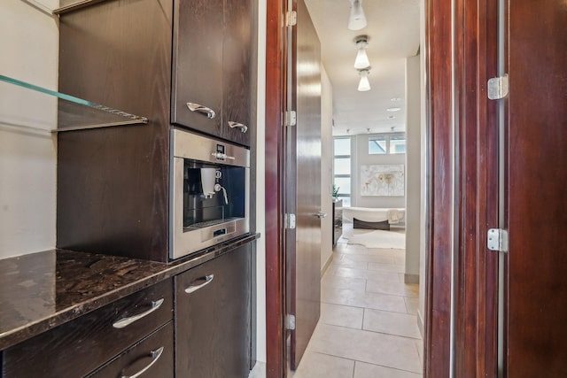 kitchen featuring dark stone counters, dark brown cabinetry, and light tile patterned floors