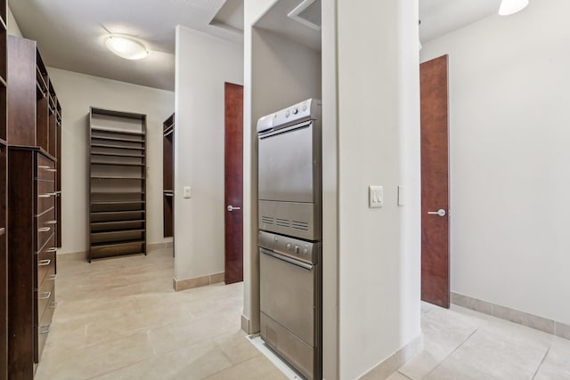 hall with light tile patterned flooring, visible vents, and baseboards