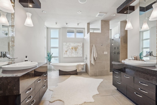 full bathroom featuring a freestanding tub, a sink, visible vents, tile patterned floors, and a stall shower