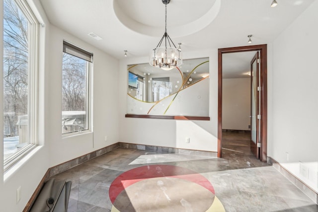 unfurnished dining area with baseboards, a raised ceiling, visible vents, and a notable chandelier