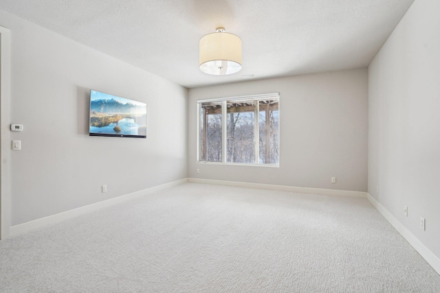 carpeted spare room featuring baseboards and a textured ceiling