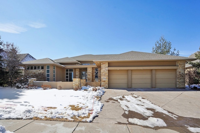 prairie-style house featuring a garage, stone siding, and concrete driveway