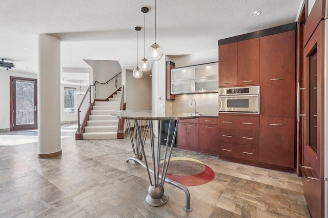 9730 Sky Ln, Eden Prairie, MN 55347 - kitchen featuring stainless steel oven, hanging light fixtures, a sink, glass insert cabinets, and a textured ceiling