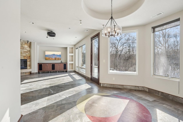 9730 Sky Ln, Eden Prairie, MN 55347 - unfurnished dining area with healthy amount of natural light, a chandelier, baseboards, and a stone fireplace