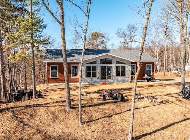 rear view of property with stone siding and a shingled roof