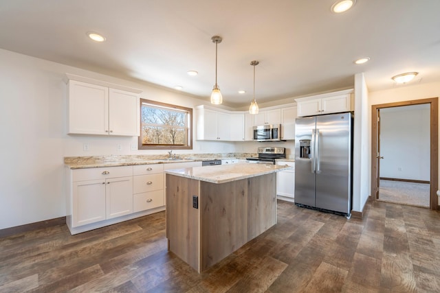 kitchen with white cabinets, a center island, light stone countertops, and stainless steel appliances