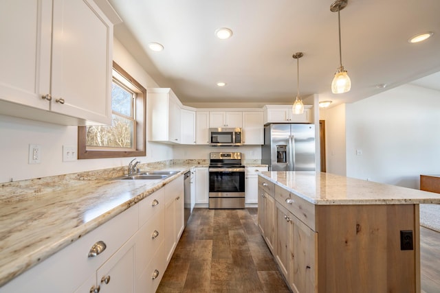 kitchen featuring light stone counters, a kitchen island, dark wood finished floors, a sink, and appliances with stainless steel finishes