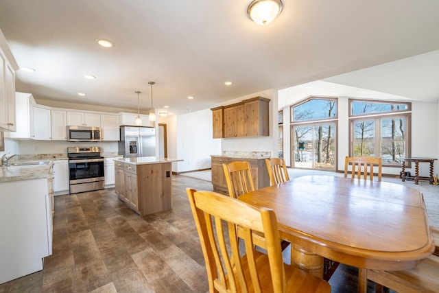 kitchen with a kitchen island, lofted ceiling, recessed lighting, a sink, and appliances with stainless steel finishes