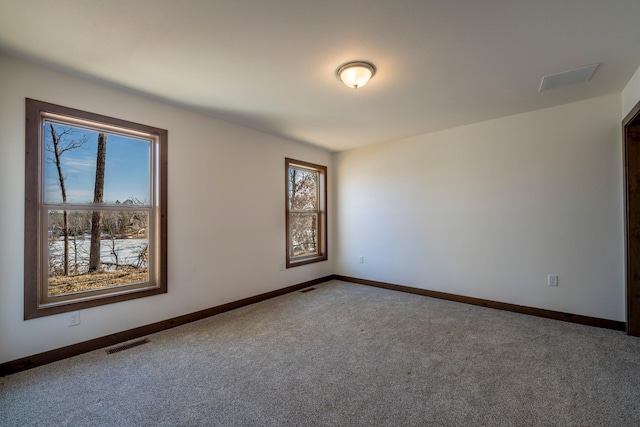 spare room featuring baseboards, visible vents, and carpet floors