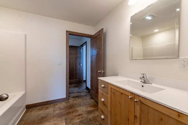 full bathroom with vanity, wood finished floors, a bathing tub, baseboards, and visible vents