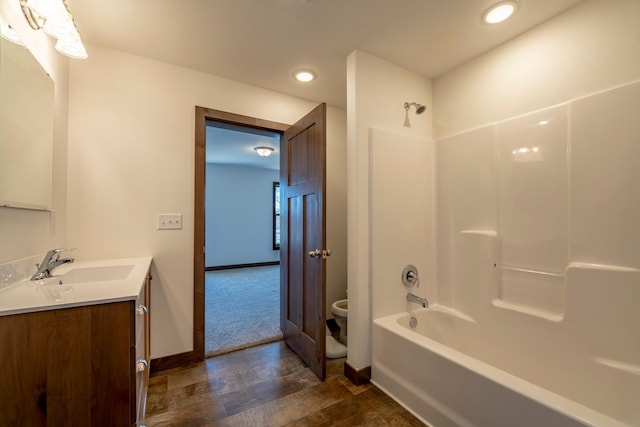 bathroom with toilet, wood finished floors, shower / bath combination, baseboards, and vanity