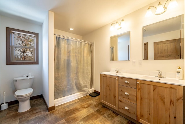 bathroom with double vanity, wood finished floors, toilet, and a sink