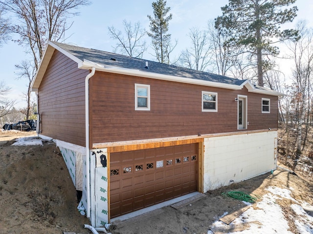 view of home's exterior with a garage and a shingled roof