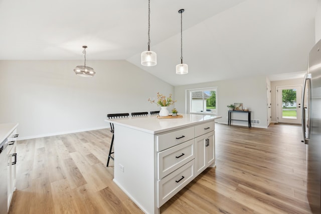 4695 3rd Street Loop NE, Saint Cloud, MN 56304 - kitchen with a breakfast bar, light wood-style flooring, white cabinetry, vaulted ceiling, and freestanding refrigerator