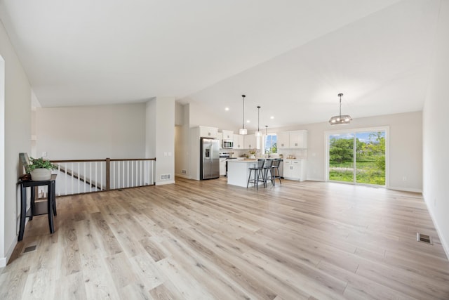 4695 3rd Street Loop NE, Saint Cloud, MN 56304 - unfurnished living room with vaulted ceiling, light wood-style flooring, baseboards, and a chandelier