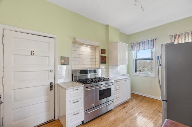 kitchen with stainless steel appliances, light countertops, white cabinets, and tasteful backsplash