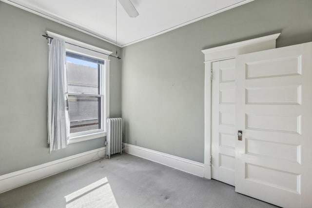 carpeted empty room featuring baseboards, a ceiling fan, and radiator